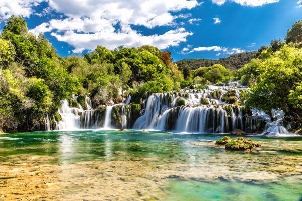Il Parco Nazionale di Krka circondato da alberi e da un cielo azzurro Il Parco Nazionale di Krka circondato da alberi e da un cielo azzurro