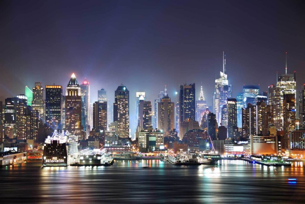 Skyline della città di notte con luci che si riflettono sull'acqua Skyline della città di notte con luci che si riflettono sull'acqua