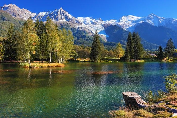 A lake surrounded by trees and mountains A lake surrounded by trees and mountains