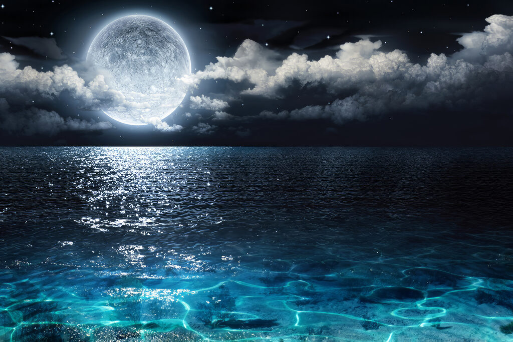 A moon over water at night