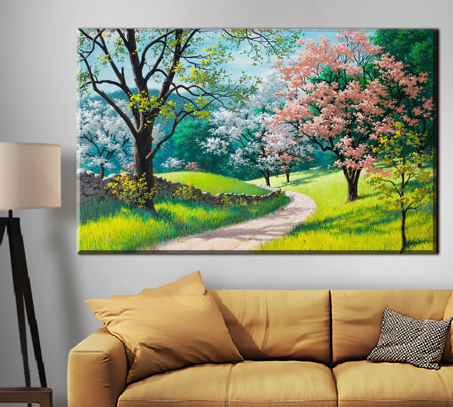 A dirt road through a grassy field with trees and a stone wall