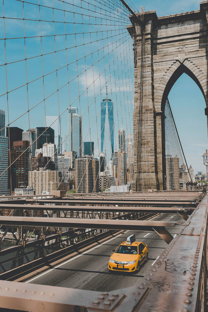 Brooklyn Bridge with a yellow taxi driving down it Brooklyn Bridge with a yellow taxi driving down it