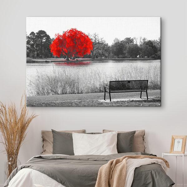 A bench by a lake with a red tree