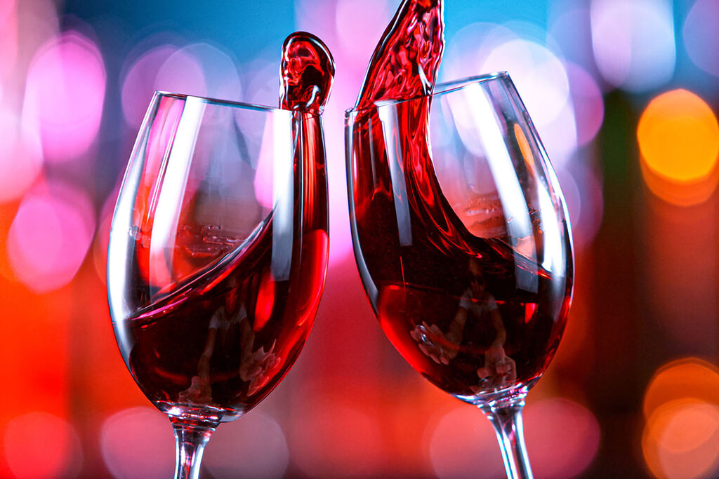 A couple of wine glasses with red liquid pouring into them