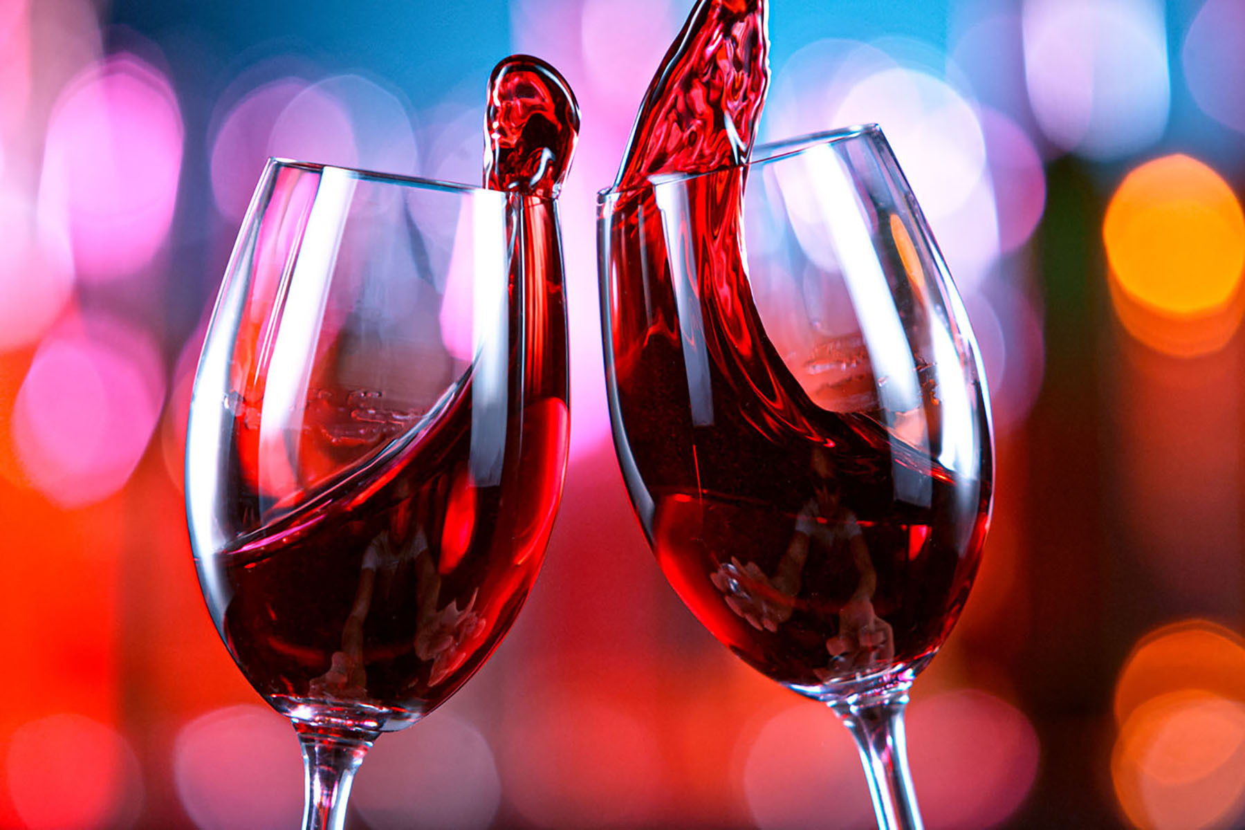 A couple of wine glasses with red liquid pouring into them