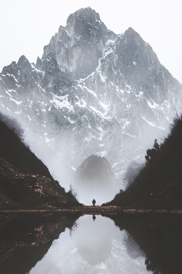 A person standing in a valley with a mountain in the background A person standing in a valley with a mountain in the background