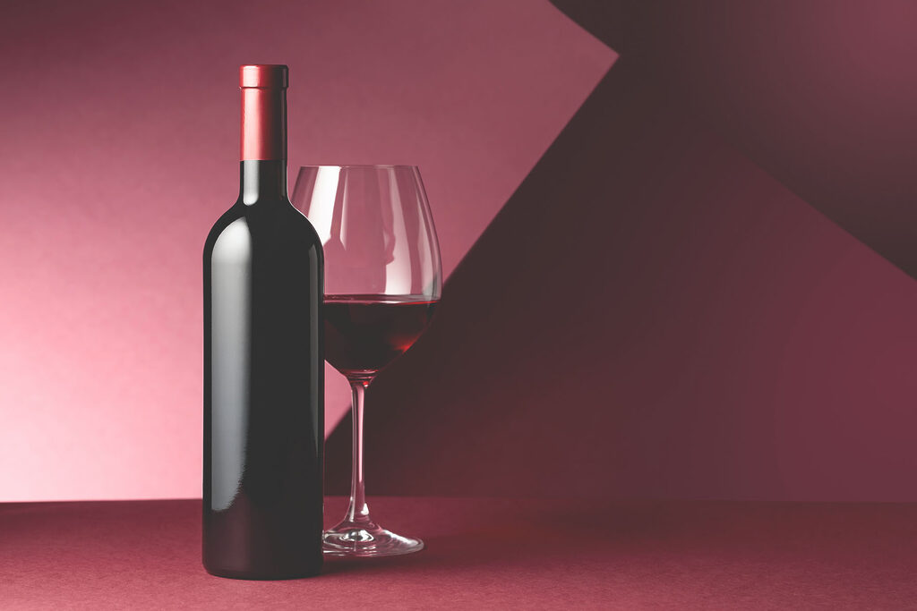 A bottle of wine next to a glass of wine