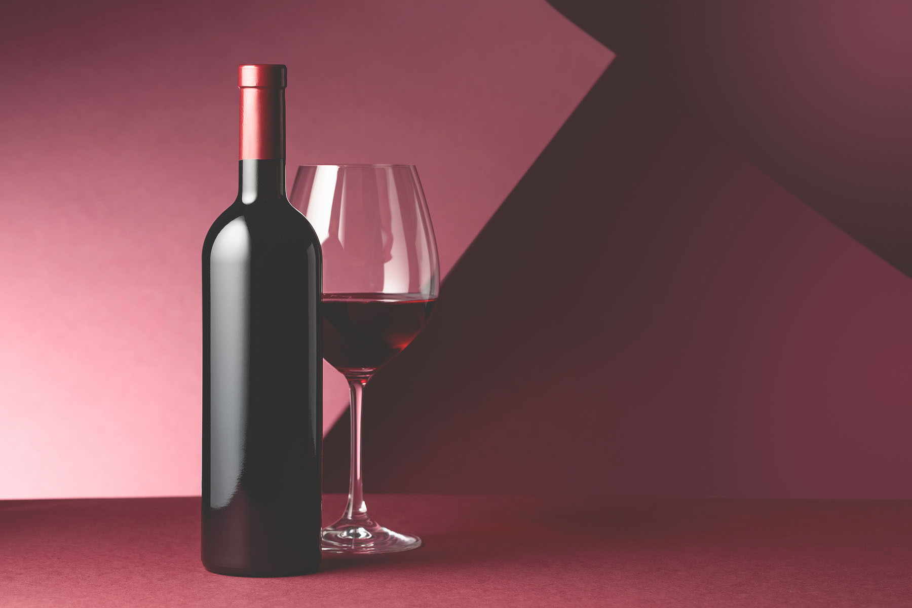 A bottle of wine next to a glass of wine