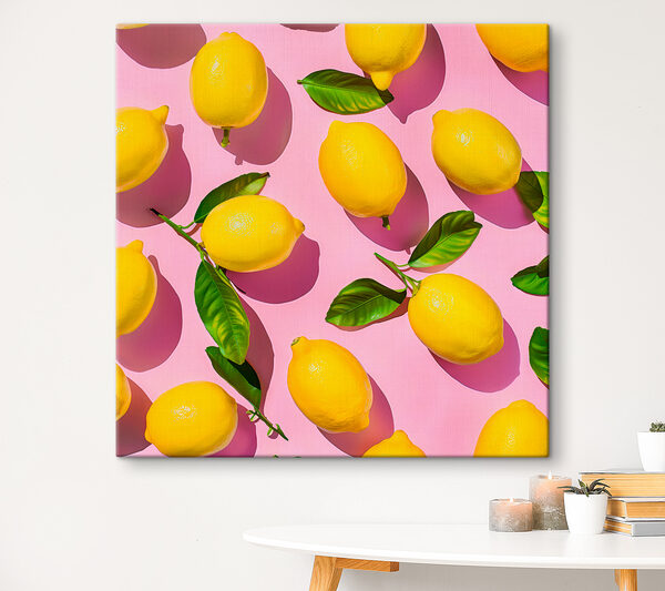 A group of lemons with leaves on a pink surface