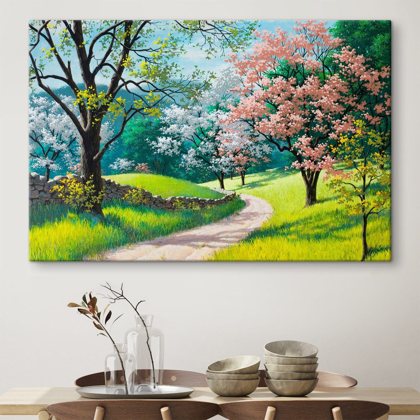 A dirt road through a grassy field with trees and a stone wall