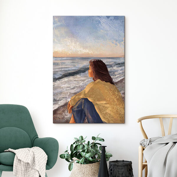A woman sitting on a beach looking out to the ocean