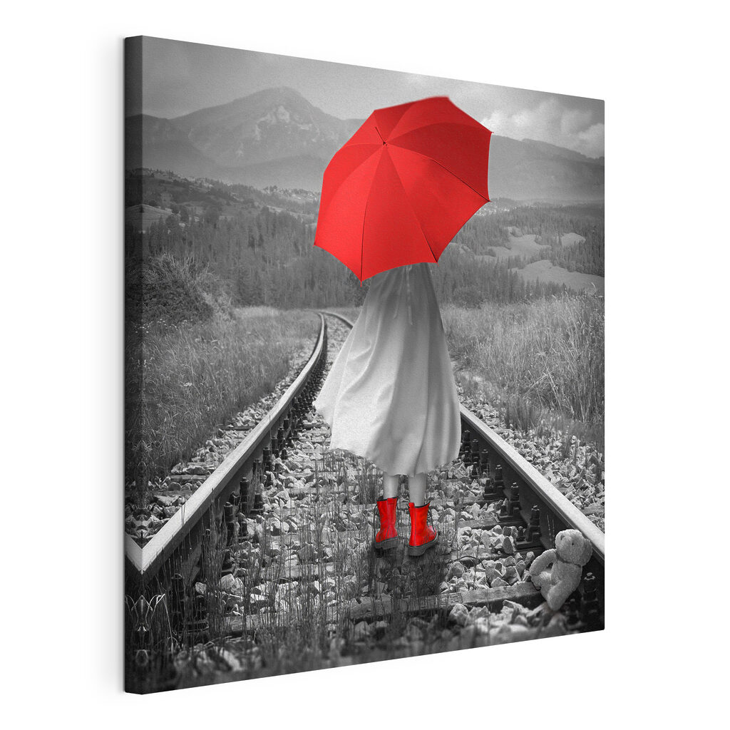 A person with a red umbrella on a train track